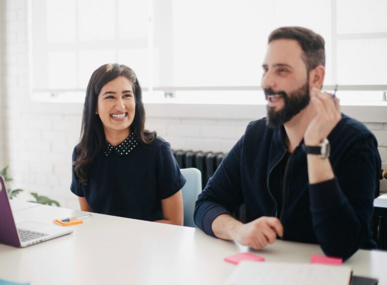 Female temporary working smiling at her colleague discussing business goals for the company