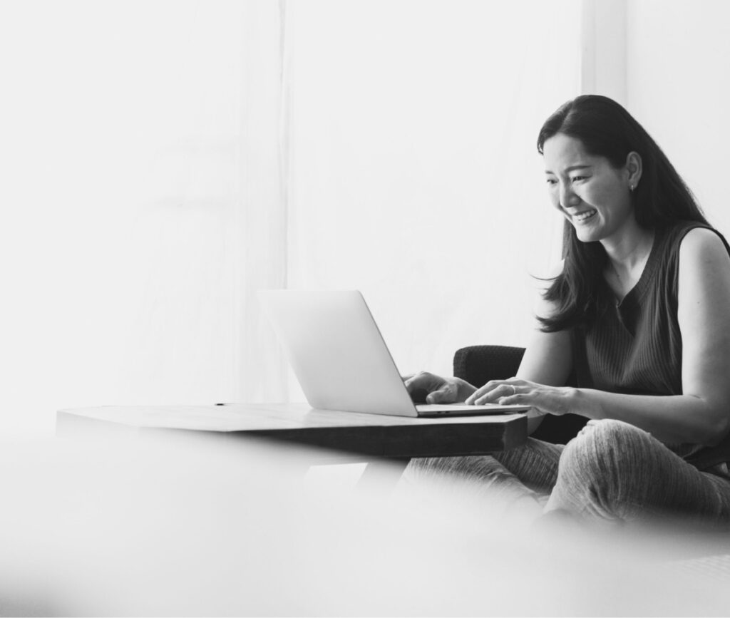 Women seen smiling at a laptop after experiencing Platform Reduces Costs and Speeds Up the Hiring Process