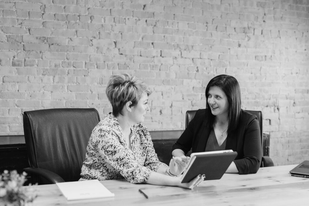 Two women in a professional setting discussing strategies, symbolizing collaboration and expertise in fractional hiring solutions for leadership and advisory roles.